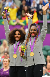 US Serena Williams (L) and Venus Williams celebrate on the podium after receiving their gold medal for winning the London 2012 Olympic Games women's doubles tennis tournament, at the All England Tennis Club in Wimbledon, southwest London, on August 5, 2012. AFP PHOTO / LUIS ACOSTA (Photo credit should read LUIS ACOSTA/AFP/GettyImages)